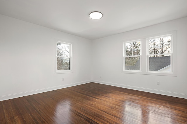 spare room featuring dark wood-style flooring and baseboards