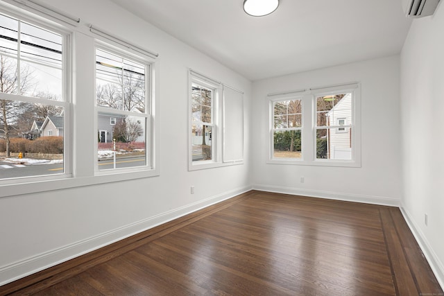 empty room with dark wood-style floors, baseboards, and an AC wall unit