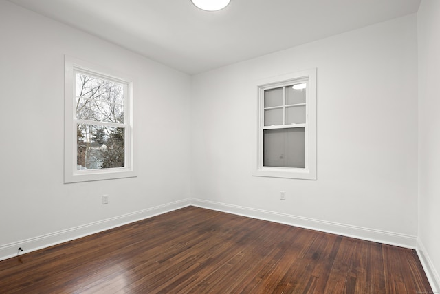 empty room with dark wood-type flooring and baseboards