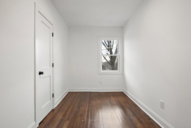 spare room featuring baseboards and dark wood finished floors