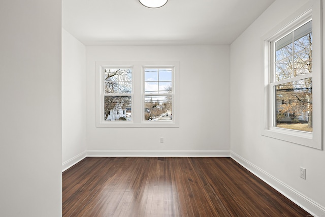 empty room featuring dark wood-type flooring, plenty of natural light, and baseboards