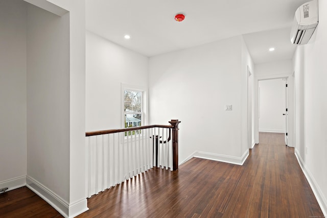 hallway featuring wood-type flooring, baseboards, an upstairs landing, and a wall mounted AC