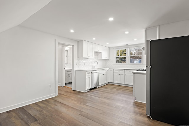 kitchen with stainless steel appliances, white cabinets, a sink, and tasteful backsplash