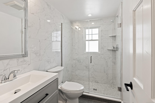 bathroom with a stall shower, visible vents, toilet, vanity, and tile walls