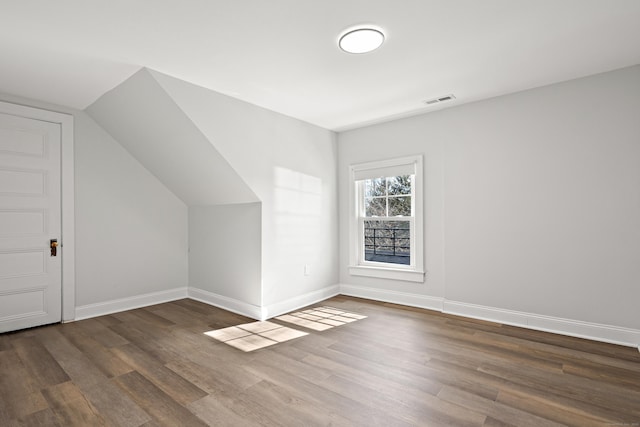 additional living space featuring vaulted ceiling, wood finished floors, visible vents, and baseboards