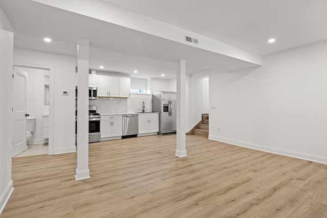 unfurnished living room with recessed lighting, visible vents, stairway, light wood-style floors, and a sink