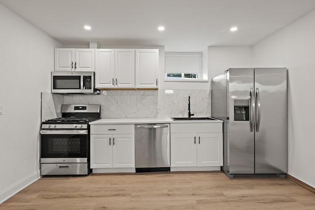 kitchen with stainless steel appliances, white cabinets, a sink, and decorative backsplash