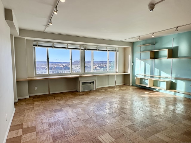 empty room featuring built in desk, a healthy amount of sunlight, a wall mounted air conditioner, and a city view