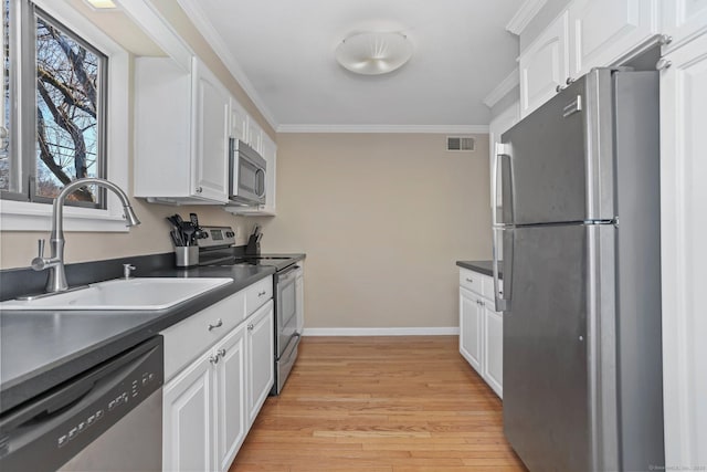 kitchen featuring dark countertops, visible vents, appliances with stainless steel finishes, and a sink