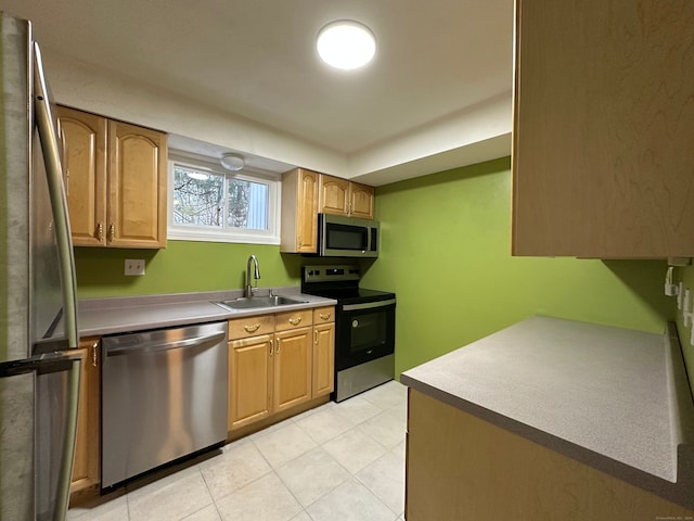 kitchen featuring light tile patterned floors, brown cabinetry, appliances with stainless steel finishes, light countertops, and a sink