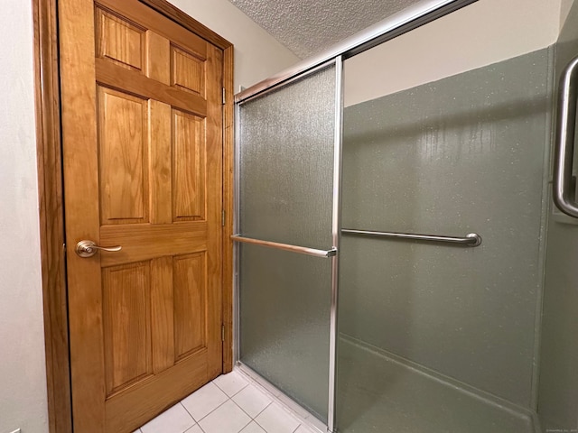 full bathroom with a textured ceiling, a shower with shower door, and tile patterned floors