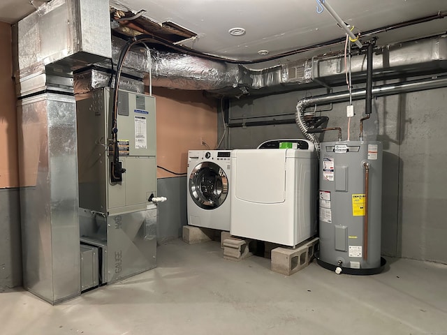 utility room featuring heating unit, water heater, and washing machine and clothes dryer