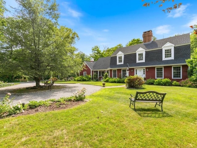 cape cod home featuring a chimney, a front yard, and a shingled roof
