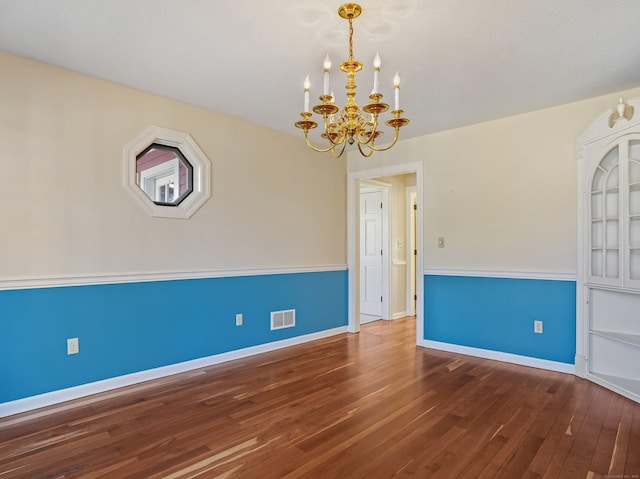 empty room featuring hardwood / wood-style floors, visible vents, baseboards, and a notable chandelier