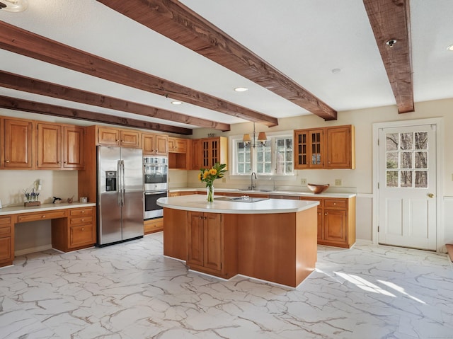 kitchen featuring light countertops, built in desk, marble finish floor, stainless steel appliances, and a sink