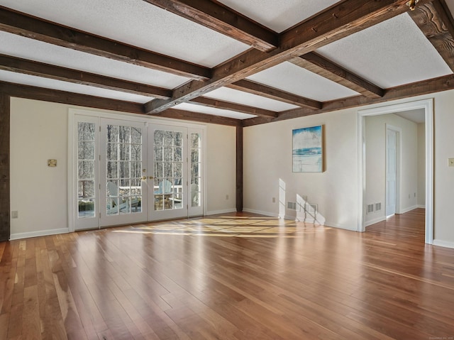 unfurnished living room featuring visible vents, beam ceiling, hardwood / wood-style flooring, french doors, and a textured ceiling