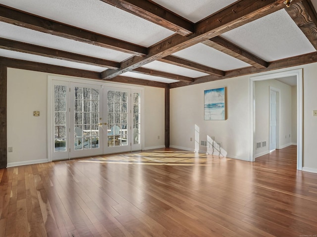 unfurnished living room featuring hardwood / wood-style floors, french doors, beamed ceiling, baseboards, and visible vents