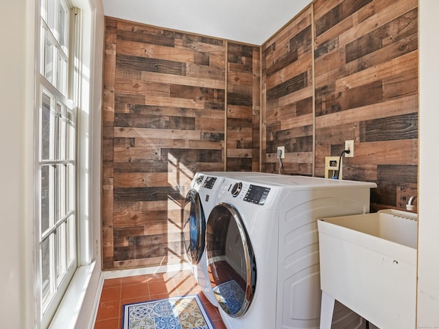 laundry area with a sink, washing machine and dryer, wooden walls, tile patterned flooring, and laundry area