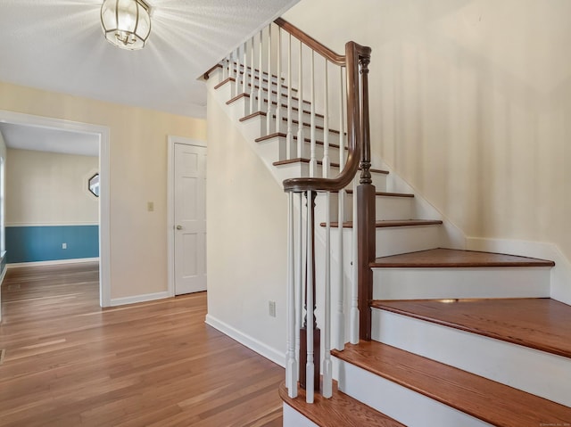 stairs with wood finished floors and baseboards