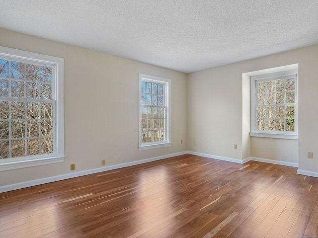 empty room with hardwood / wood-style flooring, baseboards, and a textured ceiling