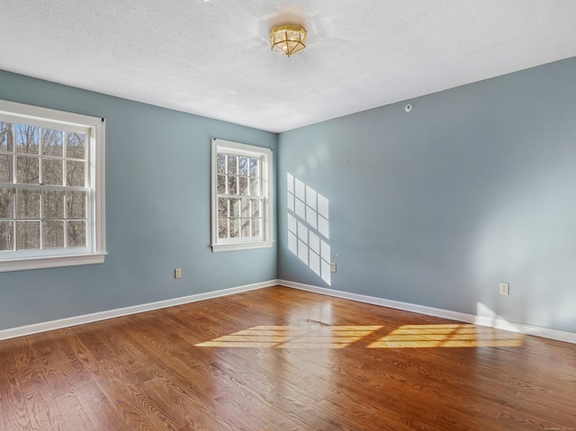 unfurnished room with wood finished floors, baseboards, and a textured ceiling