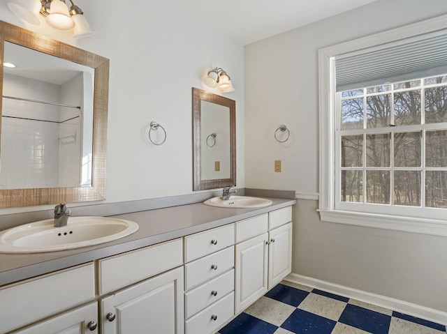 full bathroom featuring tile patterned floors, double vanity, baseboards, and a sink