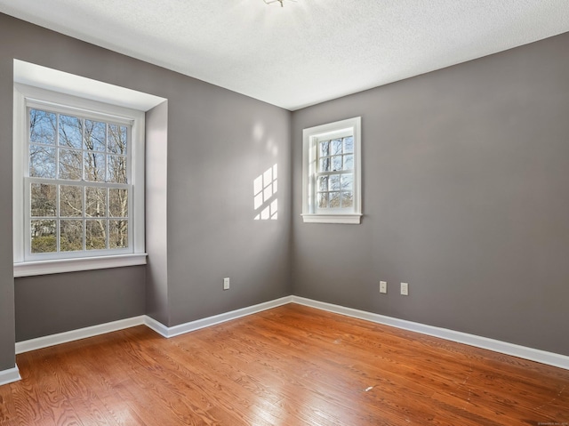 unfurnished room with baseboards, wood finished floors, and a textured ceiling