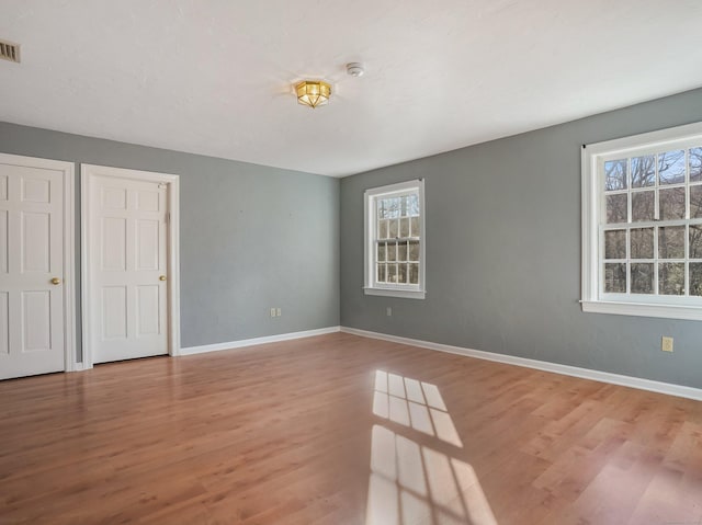 unfurnished room featuring visible vents, baseboards, and wood finished floors