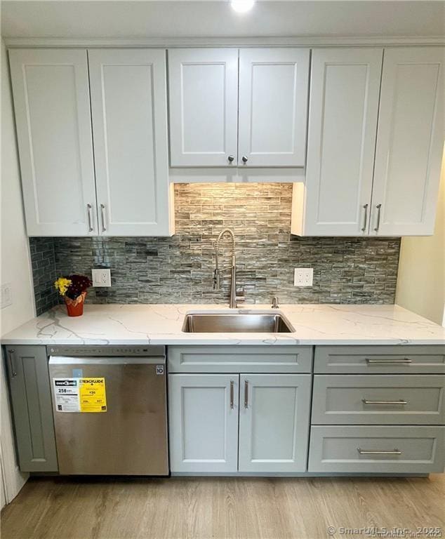 kitchen featuring sink, dishwasher, tasteful backsplash, light stone countertops, and light wood-type flooring