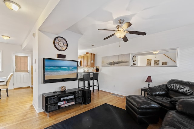 living area featuring light wood-style flooring, baseboards, and ceiling fan