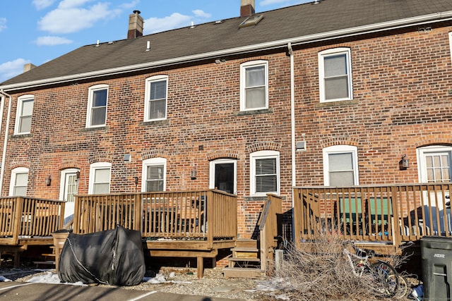 back of house with brick siding and a wooden deck