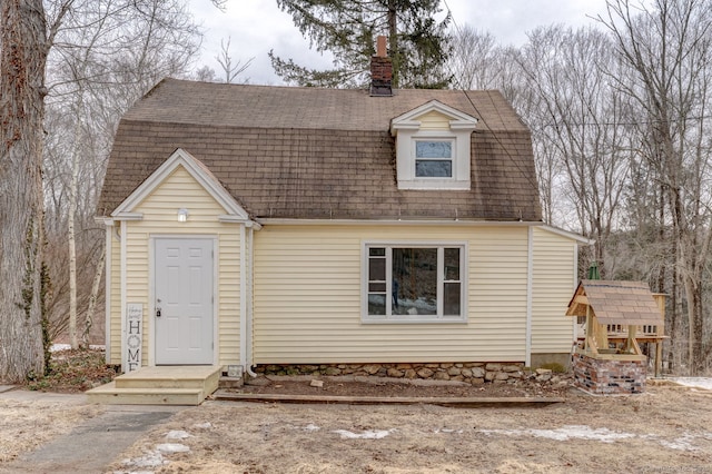 dutch colonial with roof with shingles, a chimney, and a gambrel roof