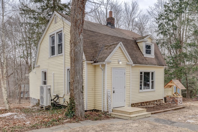 back of house featuring ac unit, a shingled roof, a chimney, and a gambrel roof