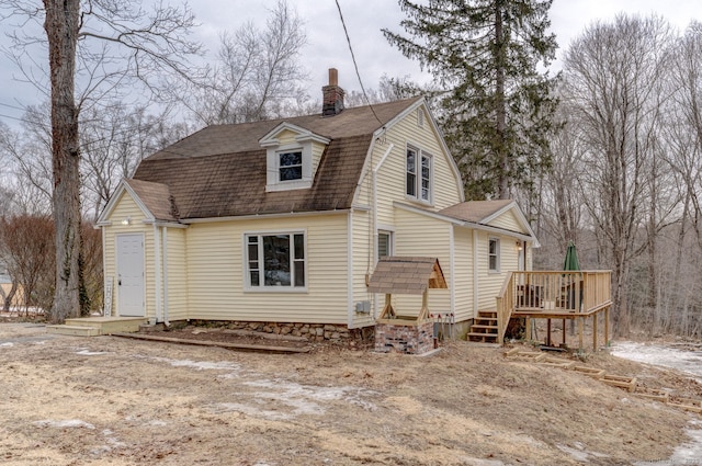 exterior space featuring roof with shingles, a chimney, a gambrel roof, and a wooden deck