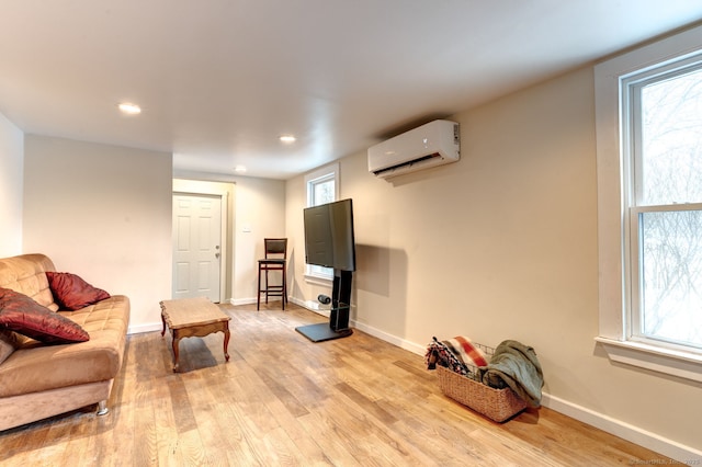 living area with light wood-style floors, a healthy amount of sunlight, baseboards, and a wall mounted AC