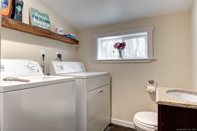 laundry room featuring laundry area, washing machine and dryer, baseboards, and a sink