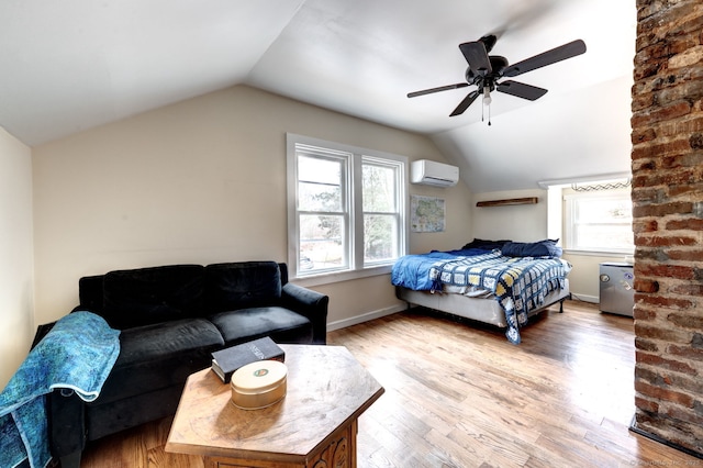 bedroom with lofted ceiling, light wood finished floors, a wall unit AC, and baseboards