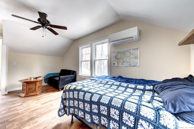 bedroom featuring vaulted ceiling, an AC wall unit, wood finished floors, and baseboards