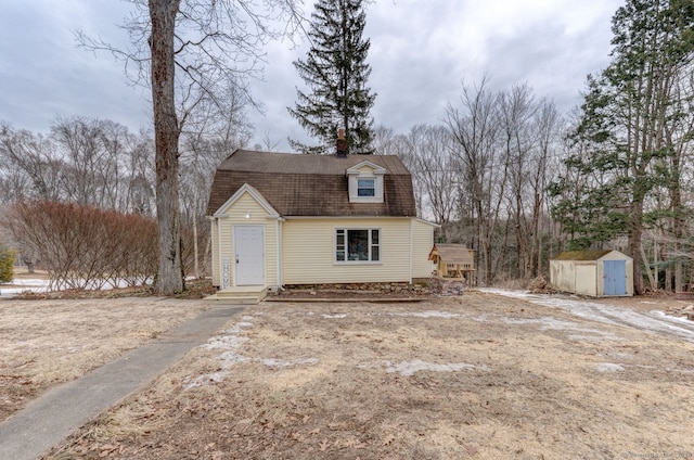 colonial inspired home with an outbuilding, a storage unit, a shingled roof, and a gambrel roof