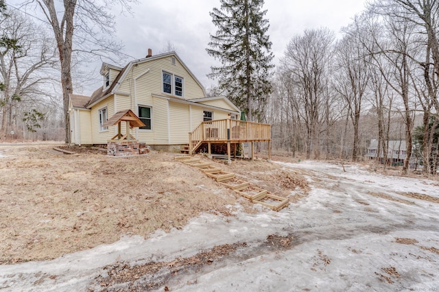 back of house featuring stairway, a wooden deck, and a gambrel roof