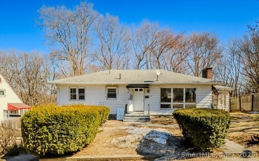 ranch-style house with a chimney and fence