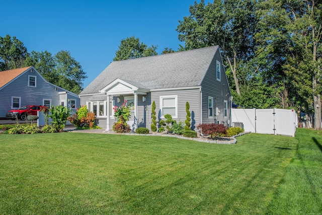 cape cod-style house featuring roof with shingles, a gate, fence, and a front yard