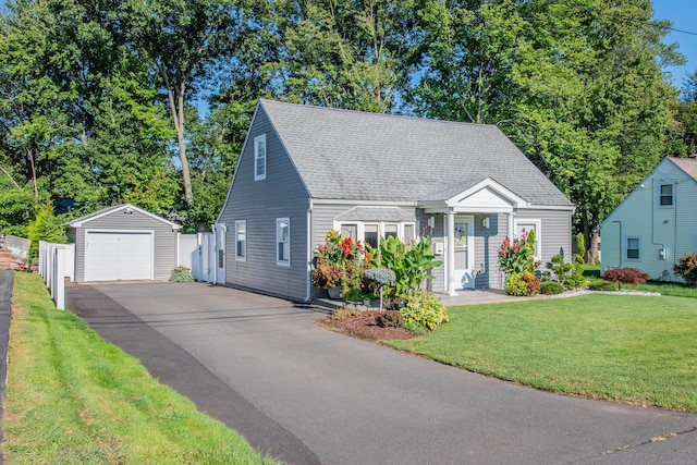 cape cod house with an outbuilding, a shingled roof, a detached garage, driveway, and a front lawn