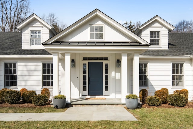 entrance to property featuring a porch, a standing seam roof, roof with shingles, and metal roof