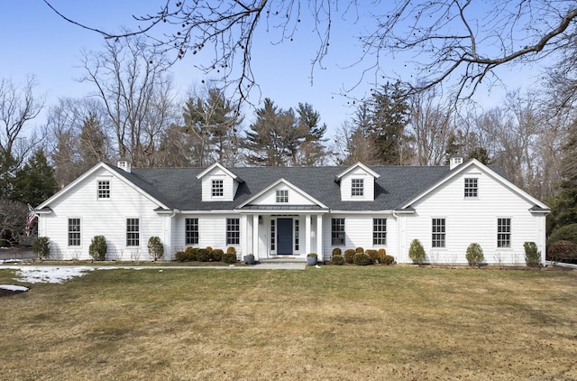 cape cod home featuring a shingled roof, a chimney, and a front yard