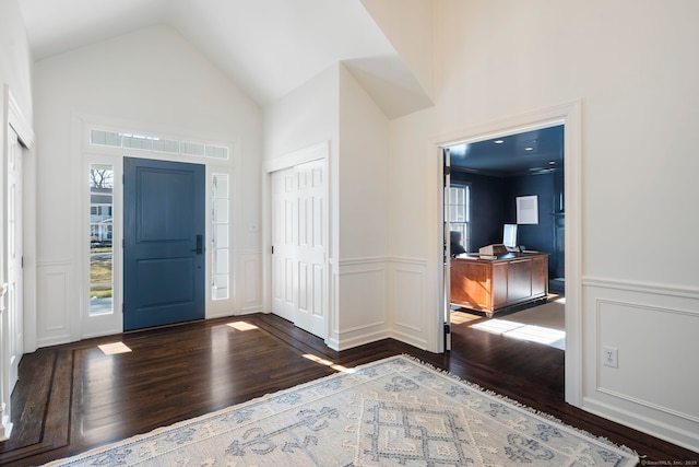 entryway with high vaulted ceiling, a decorative wall, a wainscoted wall, dark wood-style flooring, and visible vents