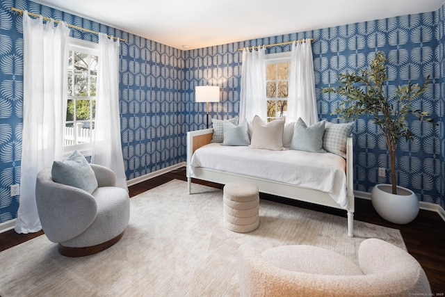 bedroom featuring baseboards, wood finished floors, and wallpapered walls