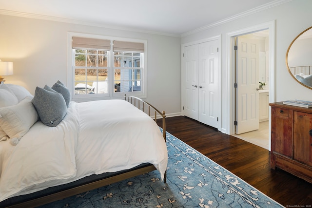 bedroom with a closet, crown molding, baseboards, and wood finished floors