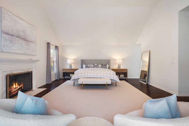 bedroom with high vaulted ceiling, a premium fireplace, wood finished floors, and baseboards