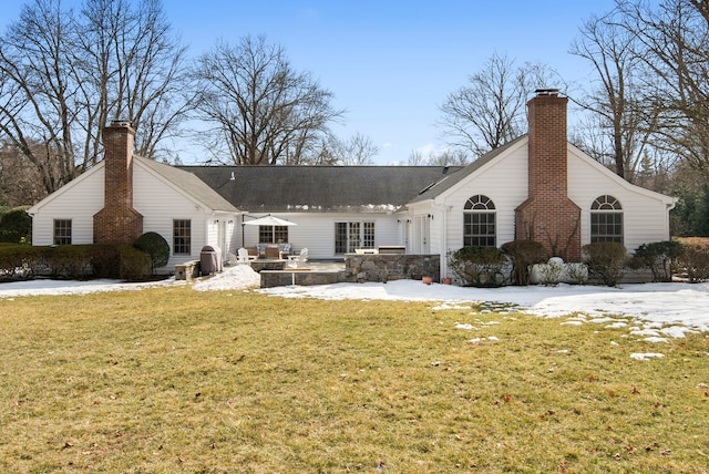 snow covered property with a patio area, a chimney, and a lawn